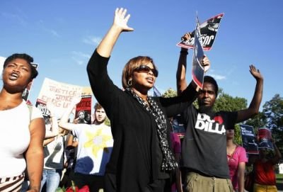 Protesters march with their hands up as they call for a thorough investigation of the shooting death of teen Michael Brown in Ferguson, Missouri, on a street in front of the White House in Washington. Photo Courtesy: Reuters